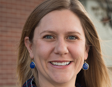 A woman with long hair wearing blue earrings.