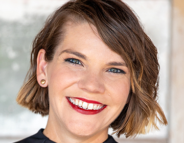 A woman with short brown hair and red lipstick.