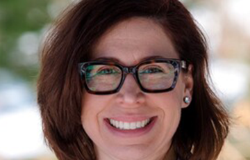 A woman with glasses smiling for the camera.