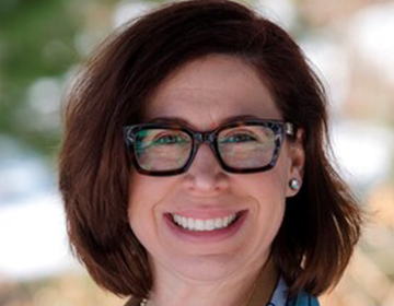 A woman with glasses smiling for the camera.