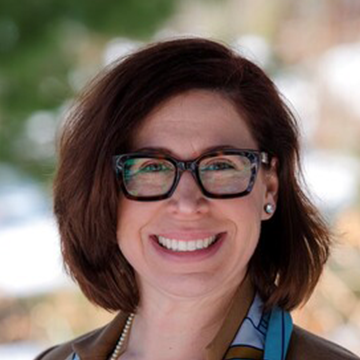 A woman with glasses smiling for the camera.