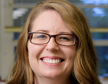 A woman with glasses smiling for the camera.