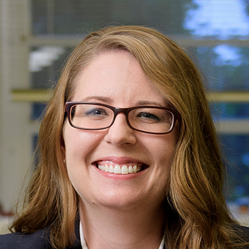 A woman with glasses smiling for the camera.