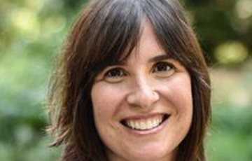 A woman with brown hair and blue shirt smiling.