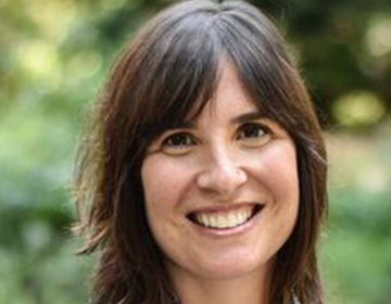 A woman with brown hair and blue shirt smiling.