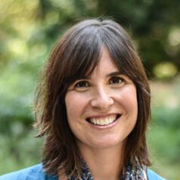 A woman with brown hair and blue shirt smiling.