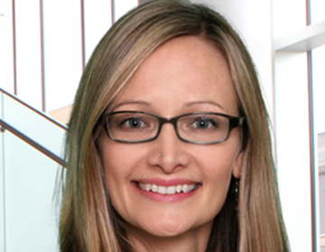 A woman with glasses smiling for the camera.