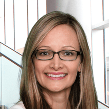 A woman with glasses smiling for the camera.