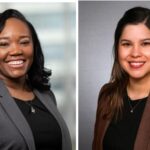 Two women in suits smiling for a picture.