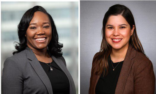 Two women in suits smiling for a picture.