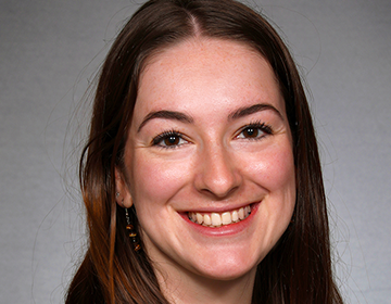 A woman with long brown hair smiles for the camera.