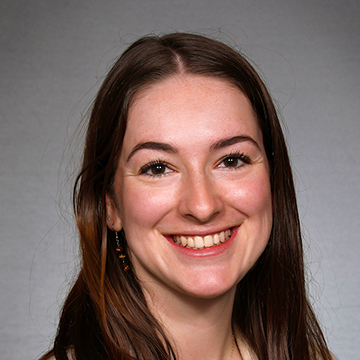 A woman with long brown hair smiles for the camera.