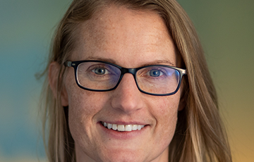 A woman with glasses smiling for the camera.