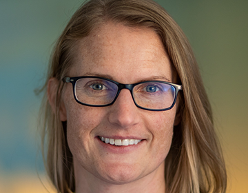 A woman with glasses smiling for the camera.