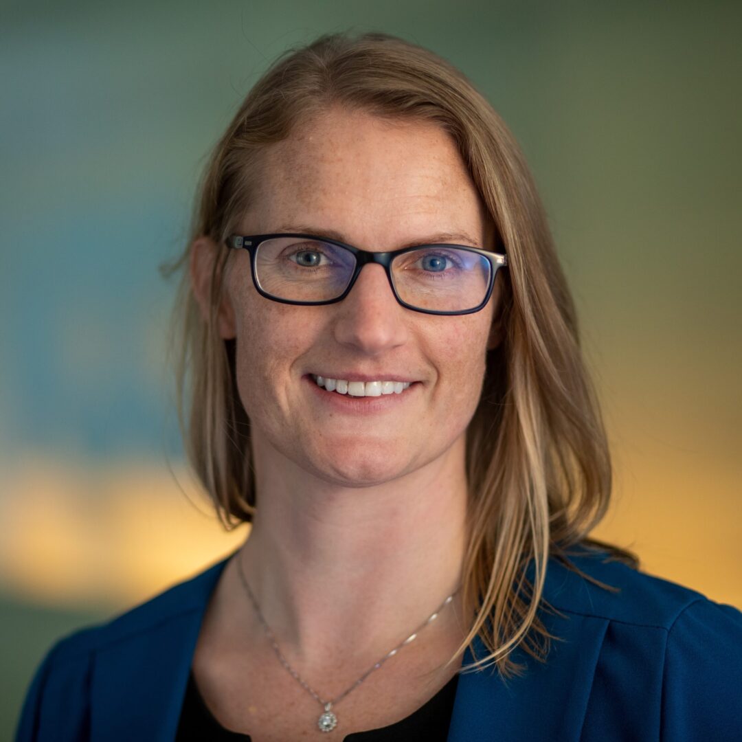 A woman with glasses smiling for the camera.