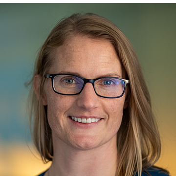 A woman with glasses smiling for the camera.