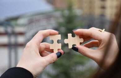 Two hands holding a puzzle piece in each hand.