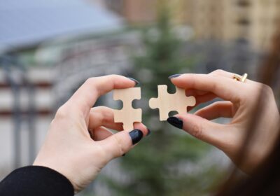 Two hands holding a puzzle piece in each hand.